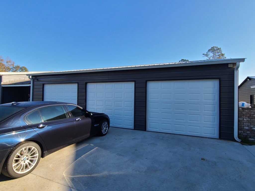 A car parked in front of three garage doors.