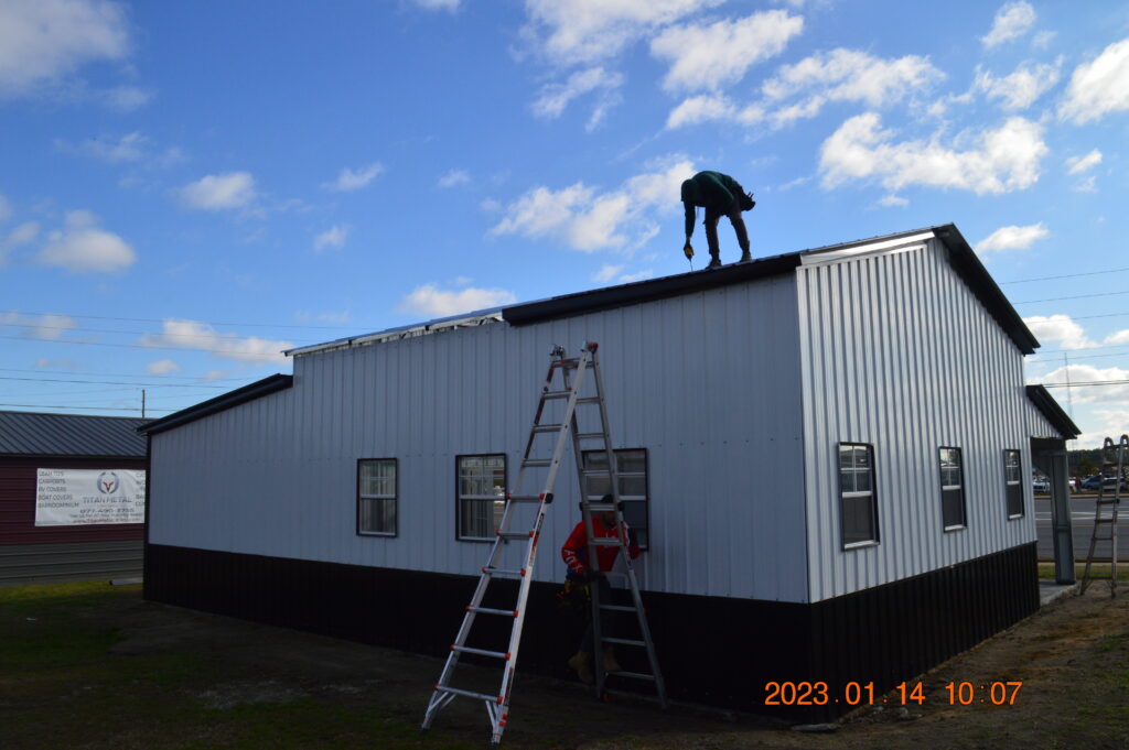 A man on a ladder and another man standing on the roof of a building.