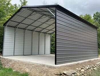 A large metal building sitting on top of a gravel road.