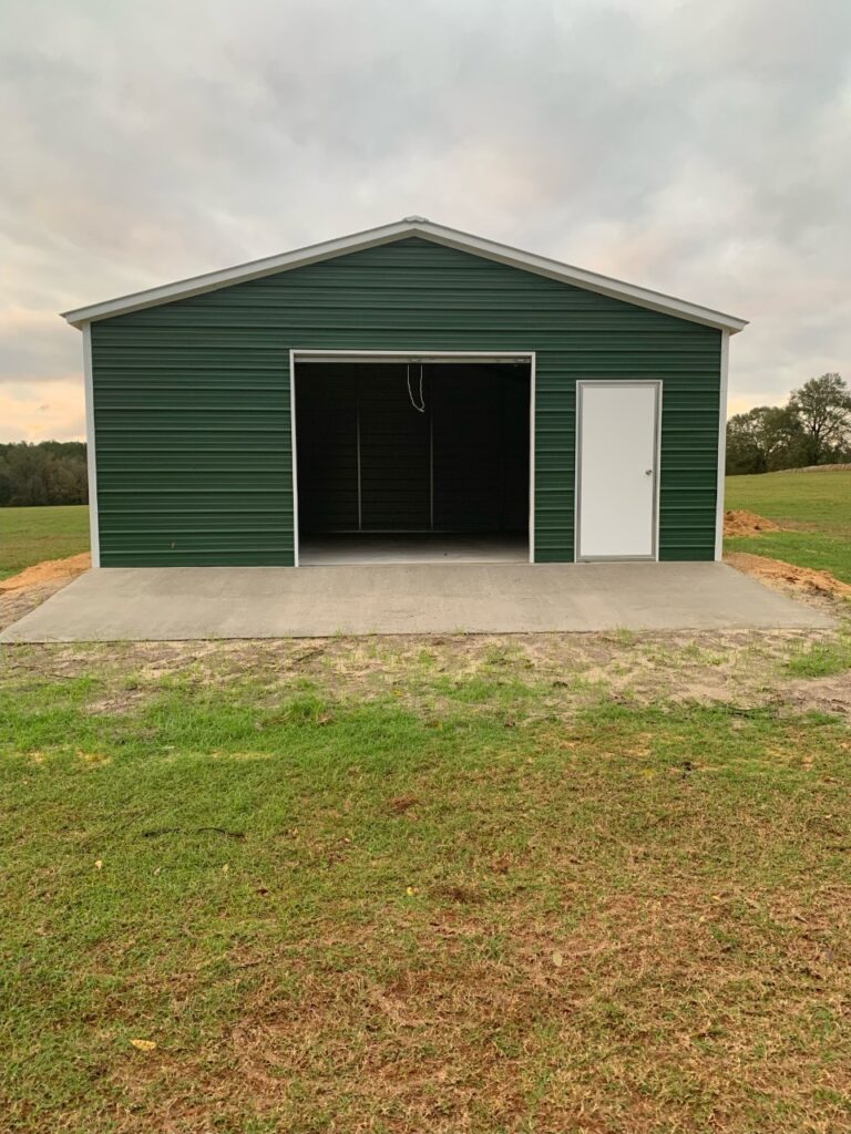 A green garage with two doors and concrete floor.