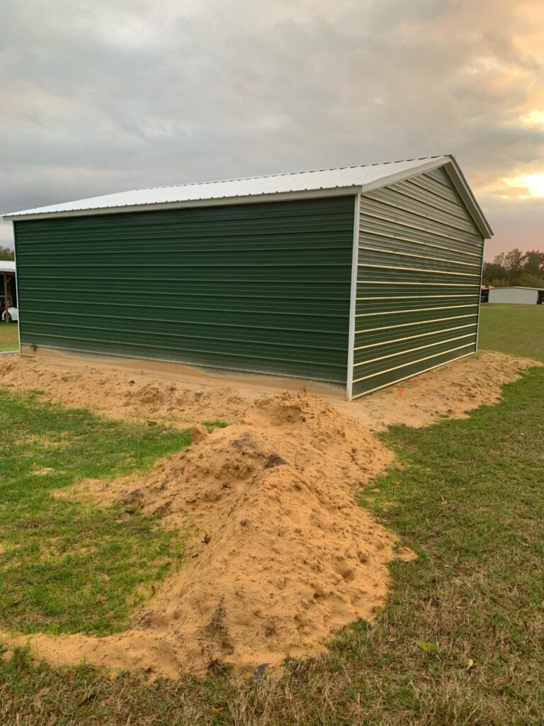 A green and white shed sitting in the middle of a field.