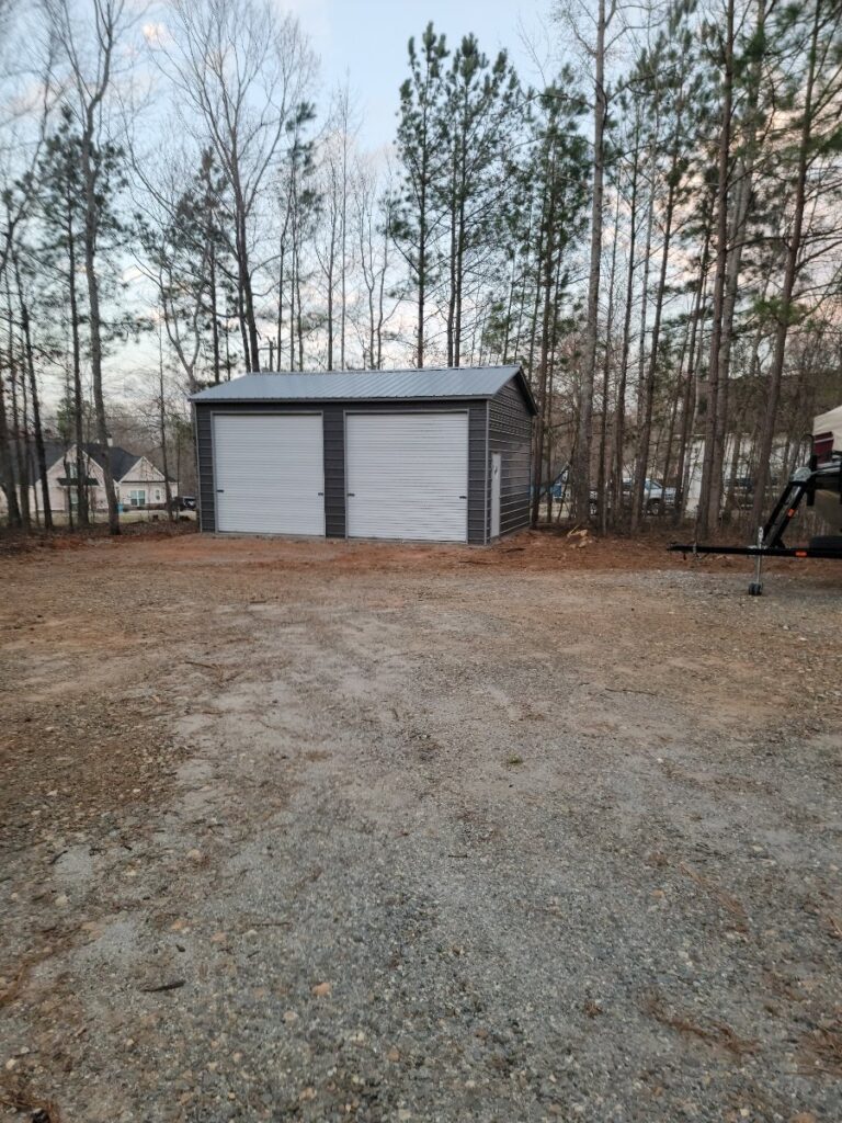 A white and gray garage in the middle of a field.