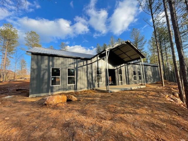 A gray metal house in the woods.