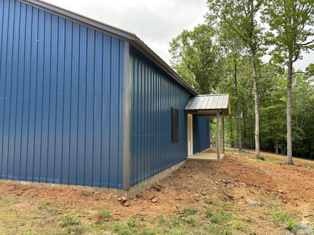 Blue metal building with white trim and a porch.